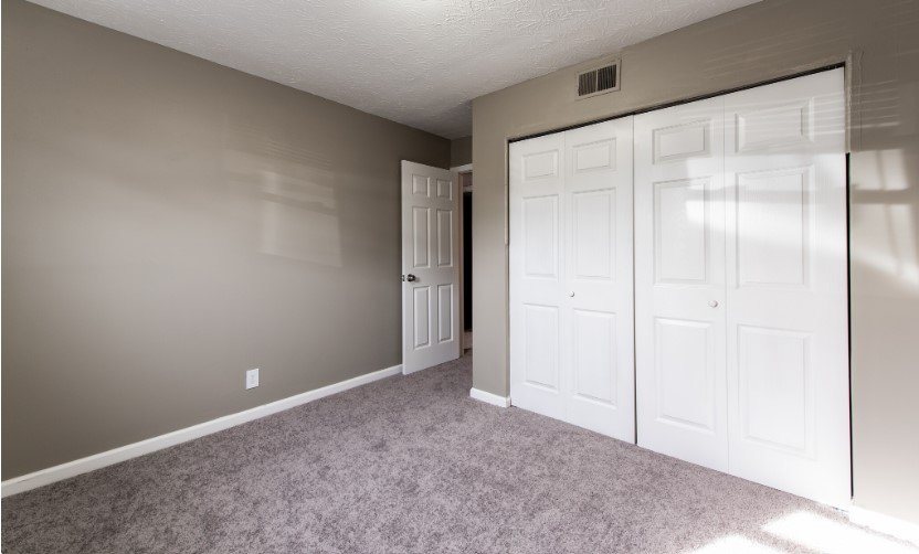 A room with a carpeted floor and white doors.